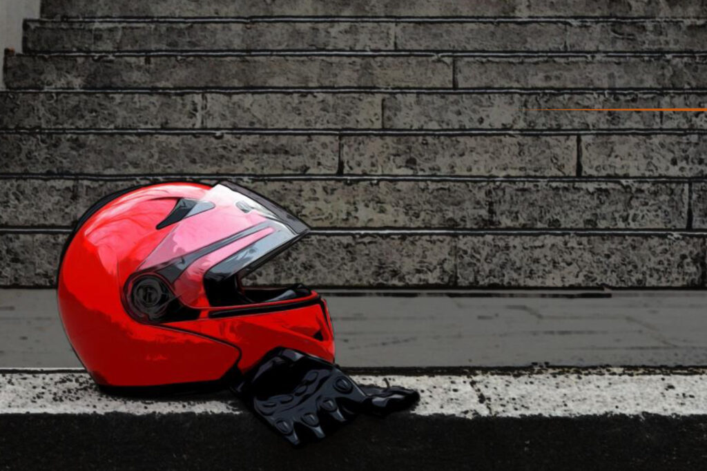 Red motorcycle helmet and gloves against a brick wall